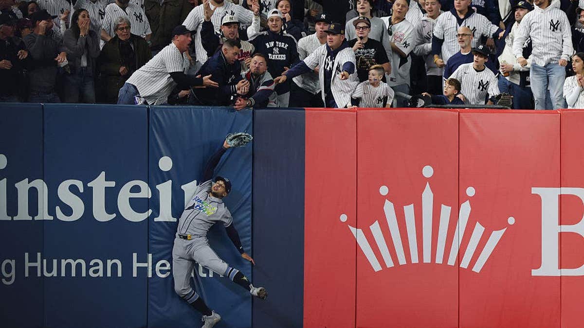 Victor Mesa Jr. of the Tampa Bay Rays reaches for a catch as fans interfere during a play at Yankee Stadium.