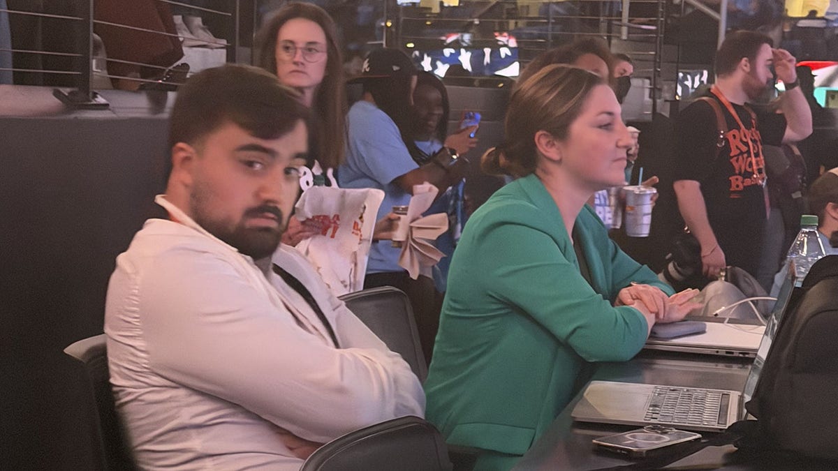Two unnamed WNBA PR staff members seen sitting during the national anthem
