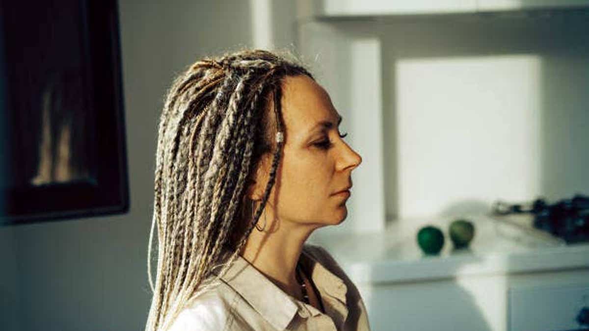 Woman with dreadlocks gazes away from camera.