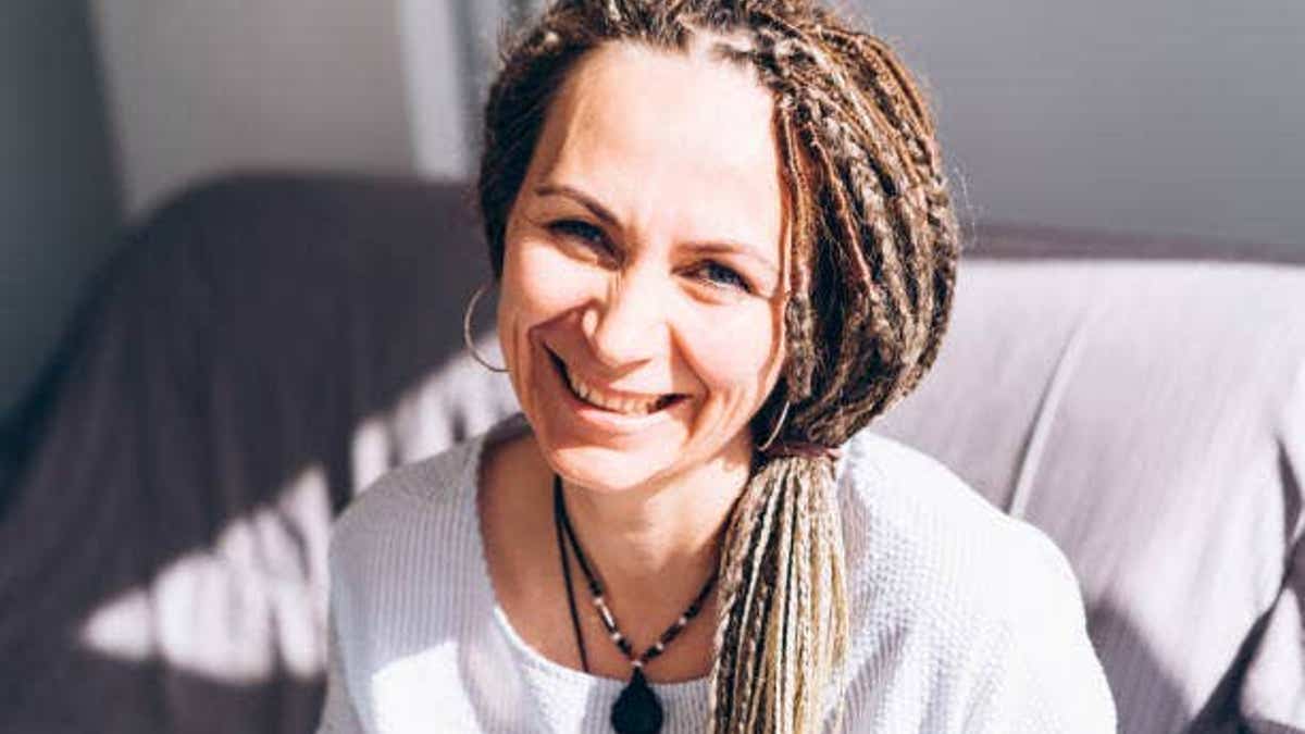Woman with dreadlocks smiling broadly in a portrait.