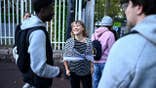 Greta Thunberg smiles while speaking with students outside a school in Saint-Denis, France