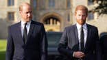 Prince William and Prince Harry in matching suits walking together.