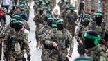 Members of the Ezz-Aldine Al-Qassam Brigades march with guns in a street in Gaza.