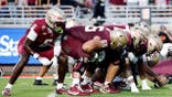 Florida State Seminoles and New Mexico State Aggies line up at the line of scrimmage during a football game.