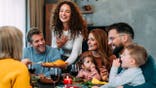 Multi-generation family seated around a dining table sharing a Thanksgiving meal with roast turkey.
