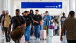 Travelers walk between terminals at DFW Airport in Dallas.