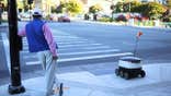 A person standing next to a delivery robot