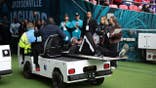 Umpire Larry Smith leaves the field on a medical buggy at Wembley Stadium.