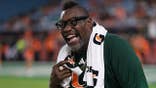 Warren Sapp laughs with former teammates during a football game.
