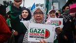 Woman raises her fist holding a placard reading Gaza Genocide at an anti-Israel protest.