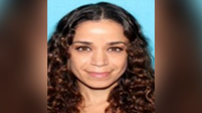 Portrait of missing woman Christina Lynn Downer with long, dark curly hair against a blue background