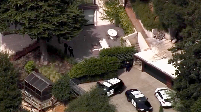 Aerial view of police vehicles and officers outside a hillside home in Oakland