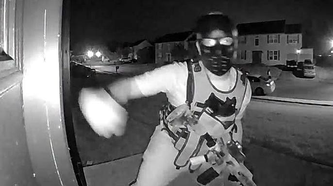 A masked individual wearing a tactical-style vest and carrying what appeared to be a rifle