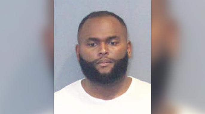 Edward Joseph Brown wearing a white T-shirt in his booking photo. He has a short-cropped haircut and beard.