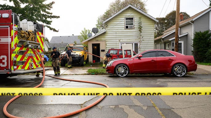 Firefighters clean blood outside a home in Erie, Pennsylvania after a family killing.