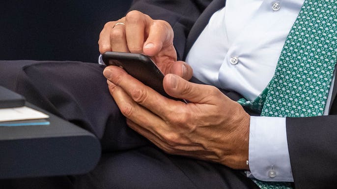 Man in a suit typing on his iPhone.