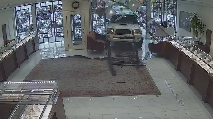 White Toyota Tacoma crashes through storefront as employees run.