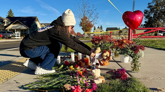 A person places flowers at a makeshift memorial on the other side of Silver Rail Elementary School in Bend, Ore., on Friday, Oct. 16, 2026, a day after a deadly shooting.