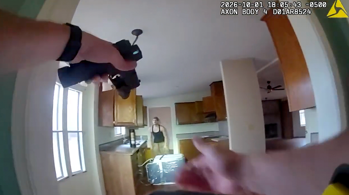 Rayven Lee Wooten stands near a kitchen doorway as a deputy points a handgun toward him