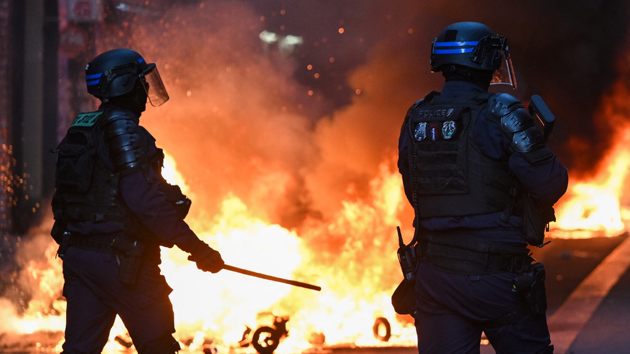 Police officers stand in front of a fire in Faubourg du Temple street as clashes erupted at Place de la Republique following an unauthorised demonstration, central Paris, on October 18, 2026.
